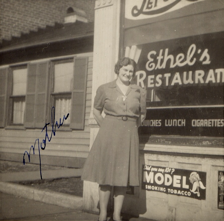 Ethel Wilson Bratton in a dress standing in front of her restaurant.  
